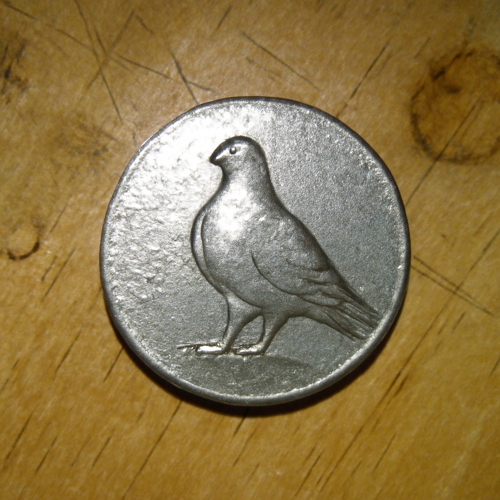 A worn United States quarter dollar photographed on a wood surface, the reverse showing a bird in place of the usual eagle
